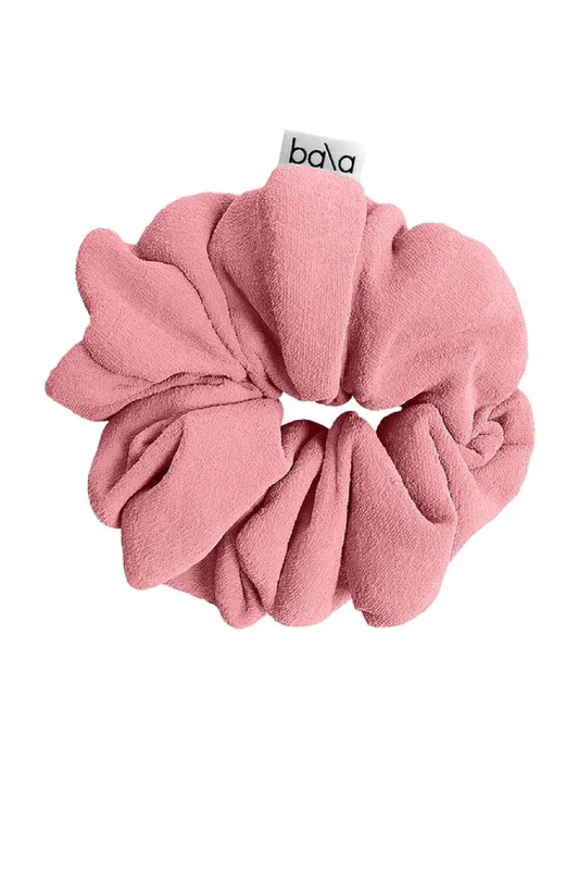 Blush pink Bala Mat Scrunchie holding a rolled exercise mat